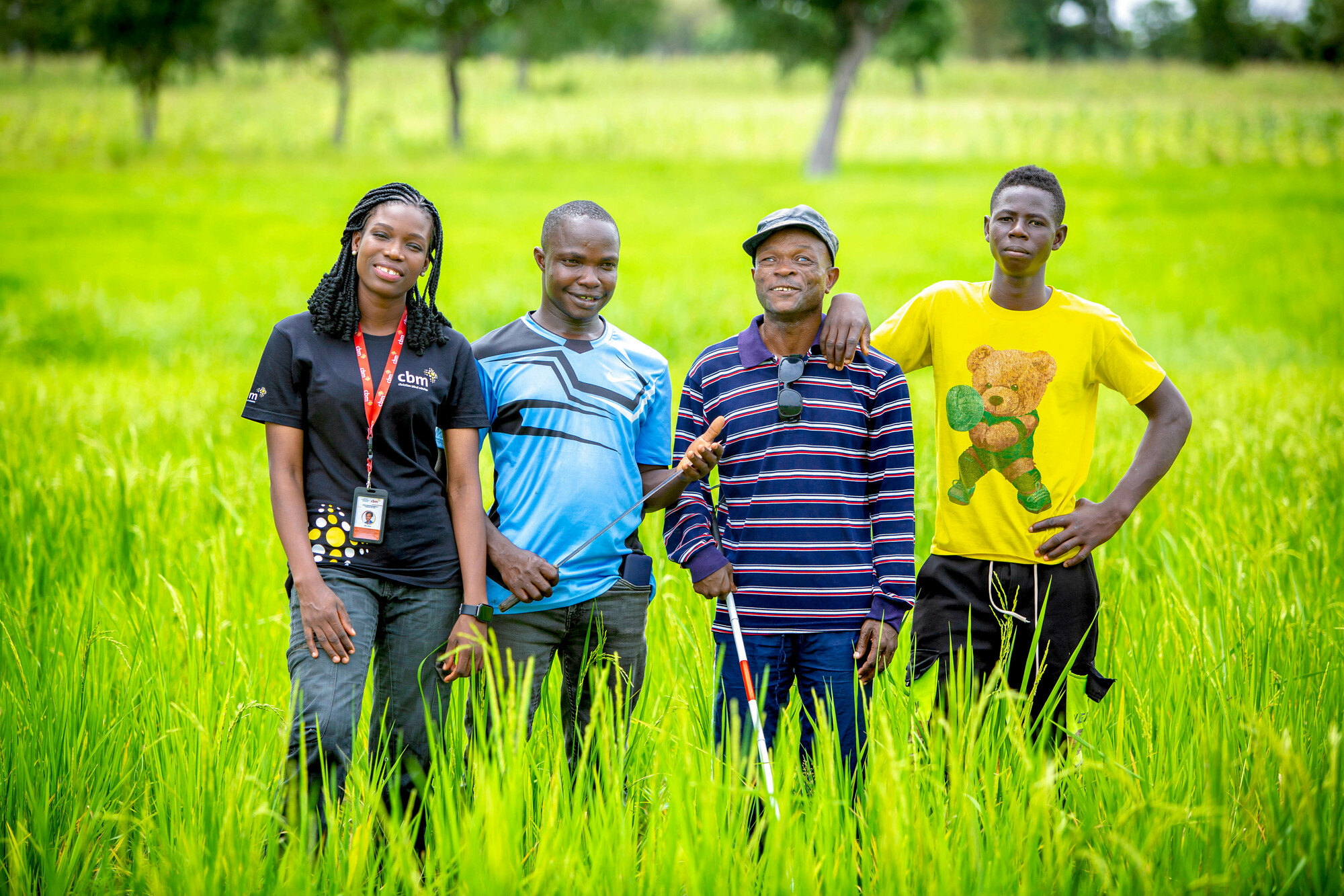 Four people standing in last green rice field. 