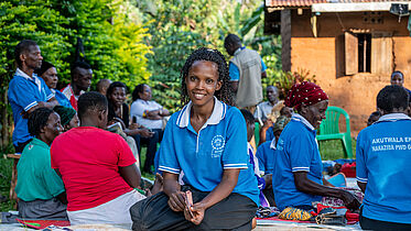 A woman counting money. In the background are members of her savings group.